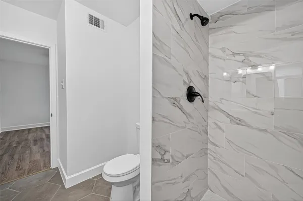 a bathroom with a granite countertop shower and a toilet