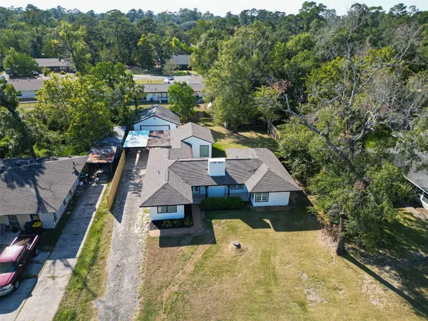 an aerial view of a house with swimming pool and large trees