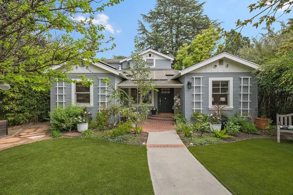 a front view of a house with a yard and potted plants