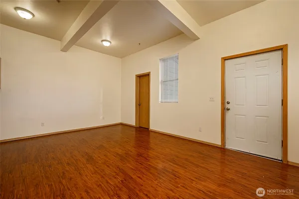 an empty room with wooden floor and windows