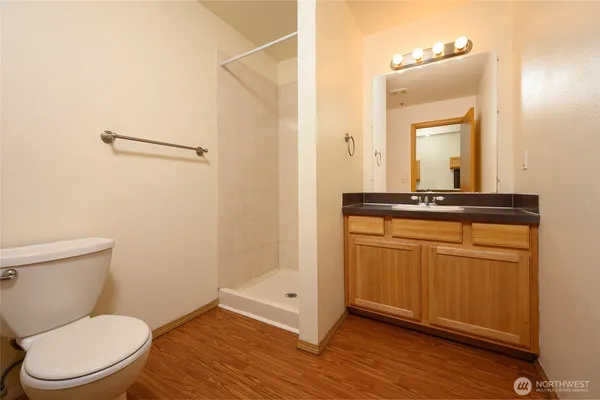 a bathroom with a toilet a sink and wooden floor