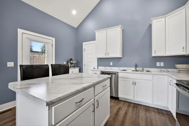 a kitchen with granite countertop white cabinets and stainless steel appliances
