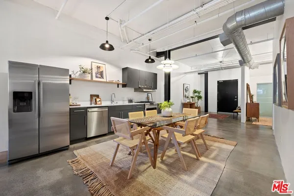 a kitchen with stainless steel appliances kitchen island granite countertop a table chairs and a refrigerator