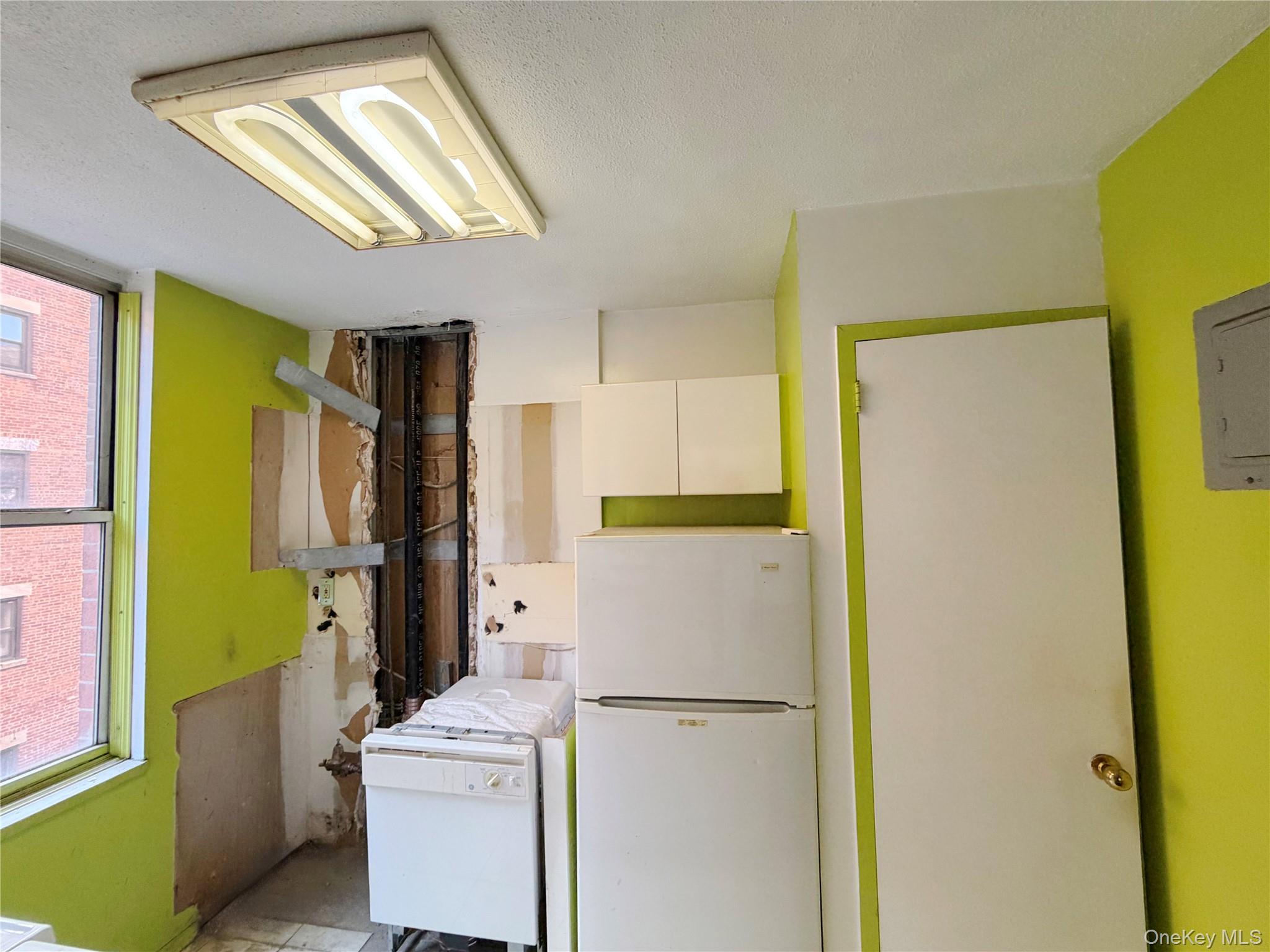 520 West 112th Street, Unit 4B Manhattan, NY 10025 - Photo 10 of 11 Kitchen with freestanding refrigerator, white cabinetry, a textured ceiling, and electric panel