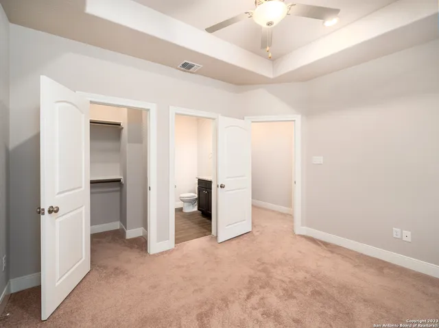 an empty room with a chandelier fan and closet