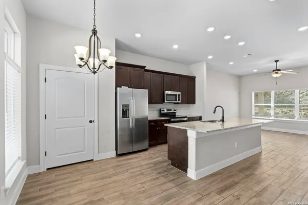 a kitchen with stainless steel appliances granite countertop a refrigerator a sink dishwasher a oven and a dining table with wooden floor