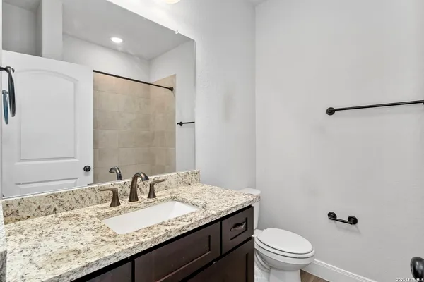 a bathroom with a granite countertop sink a toilet and a mirror