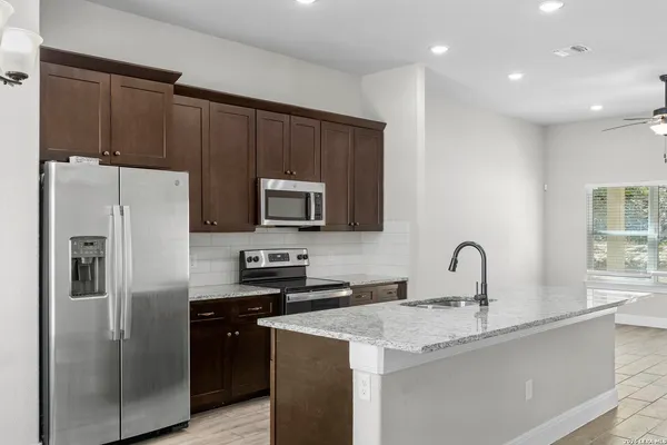 a kitchen with stainless steel appliances a refrigerator a sink a stove a microwave and cabinets