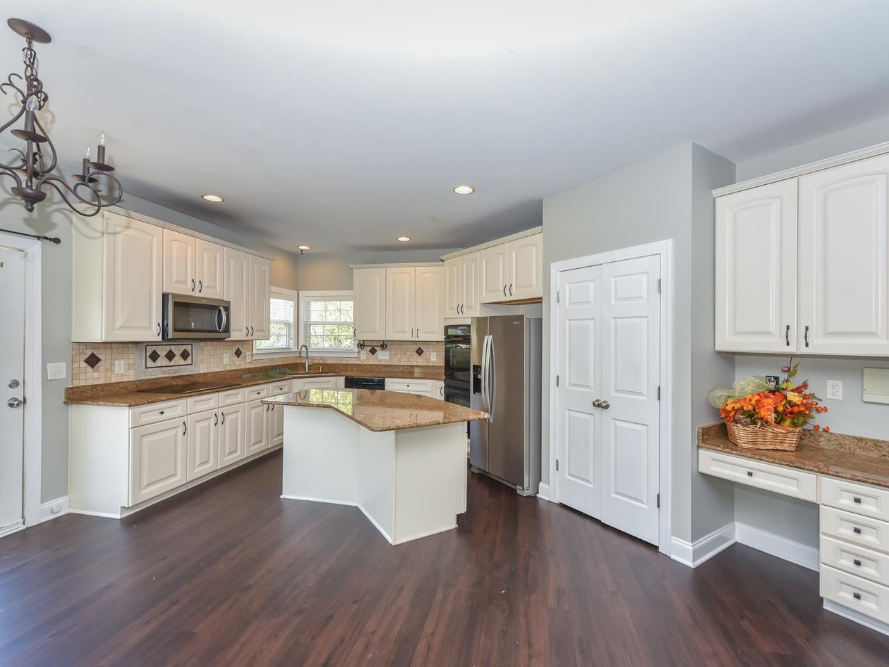 200 Quarryrock Road Holly Springs, NC 27540 - Photo 9 of 39 a kitchen with stainless steel appliances kitchen island wooden floors and white cabinets