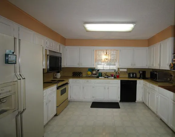 a kitchen with white cabinets and refrigerator