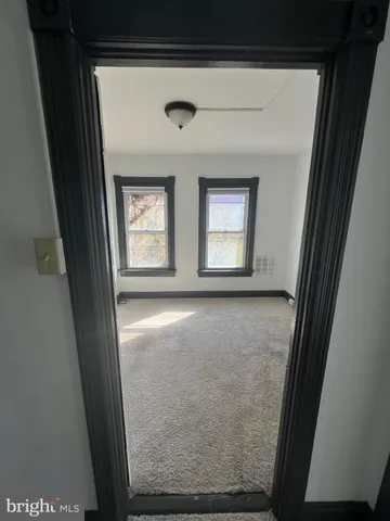 a view of an empty room with a window and dresser
