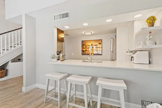 a kitchen with stainless steel appliances a sink a stove a refrigerator a counter top oven and couches