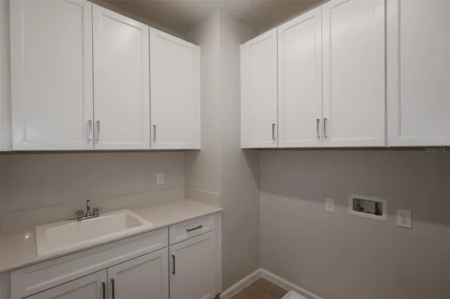 a kitchen with white cabinets and sink