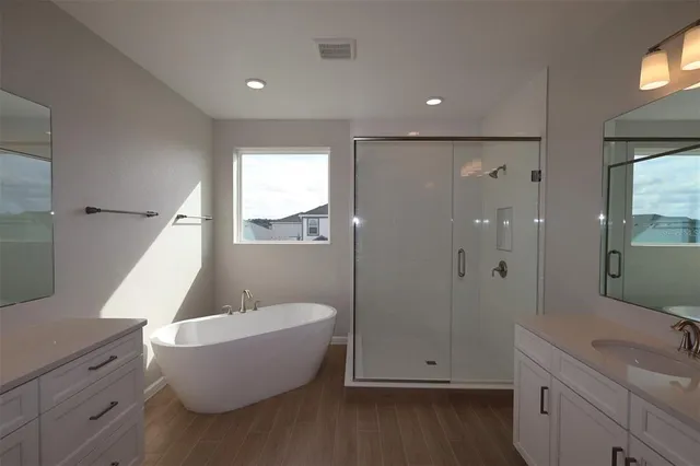 a bathroom with a white tub shower vanity and sink