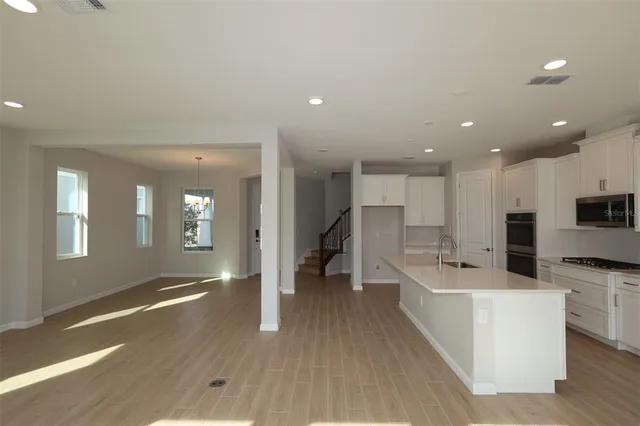a large white kitchen with lots of counter space a sink and appliances