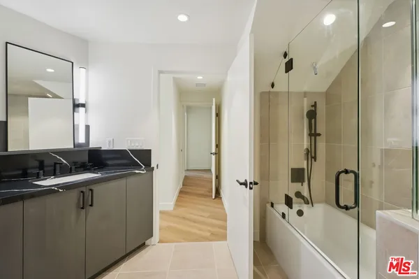 a bathroom with a granite countertop sink mirror and bathtub