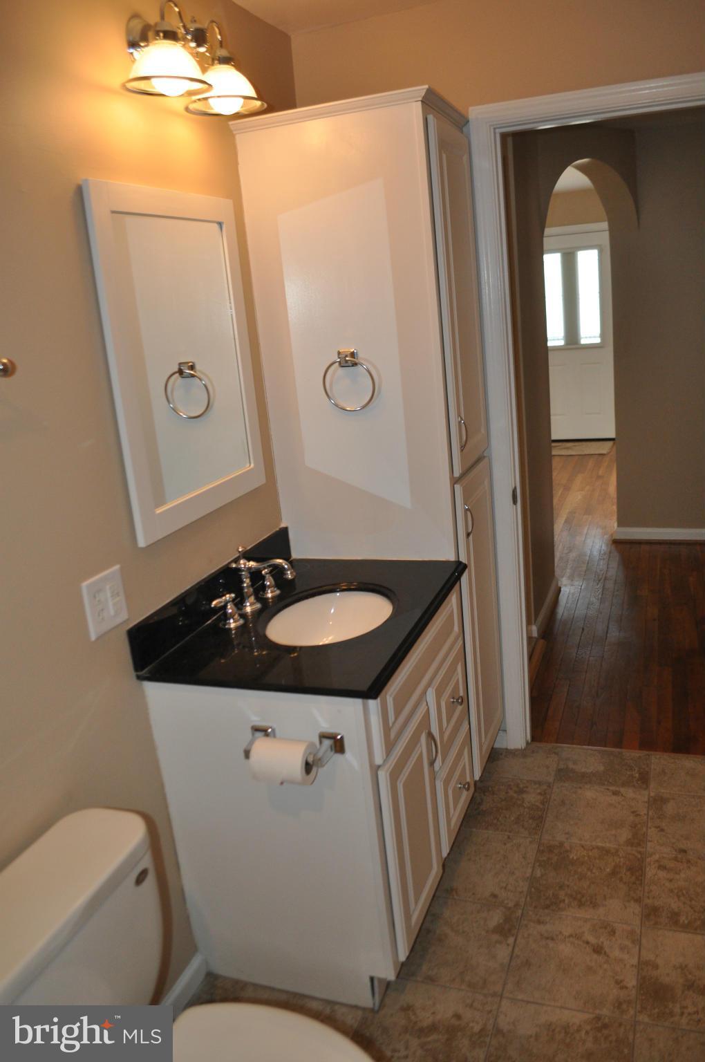 929 Woodlynn Road Baltimore, MD 21221 - Photo 12 of 25 a bathroom with a granite countertop sink a mirror and a toilet