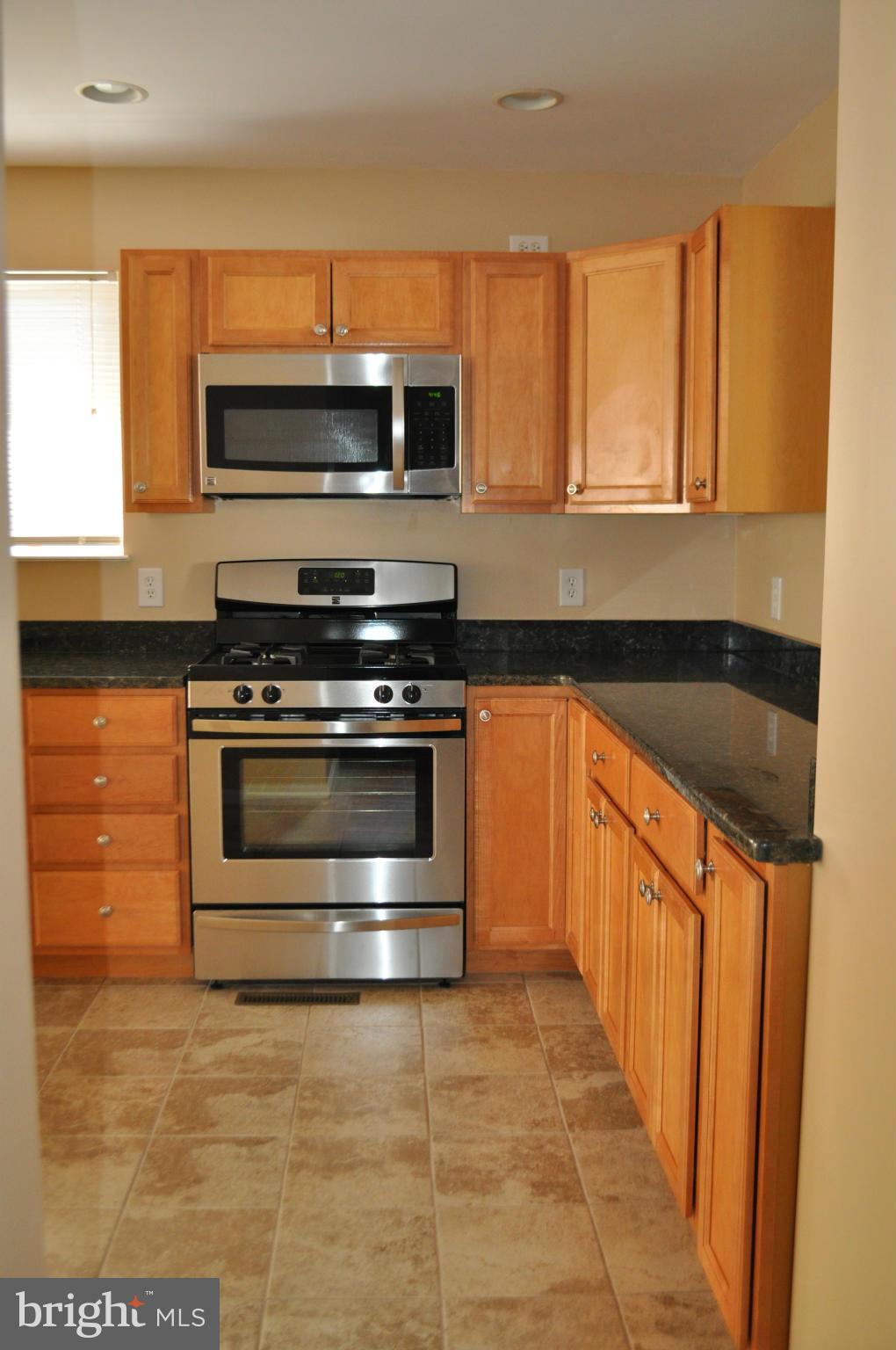 929 Woodlynn Road Baltimore, MD 21221 - Photo 4 of 25 a kitchen with granite countertop a stove and a microwave