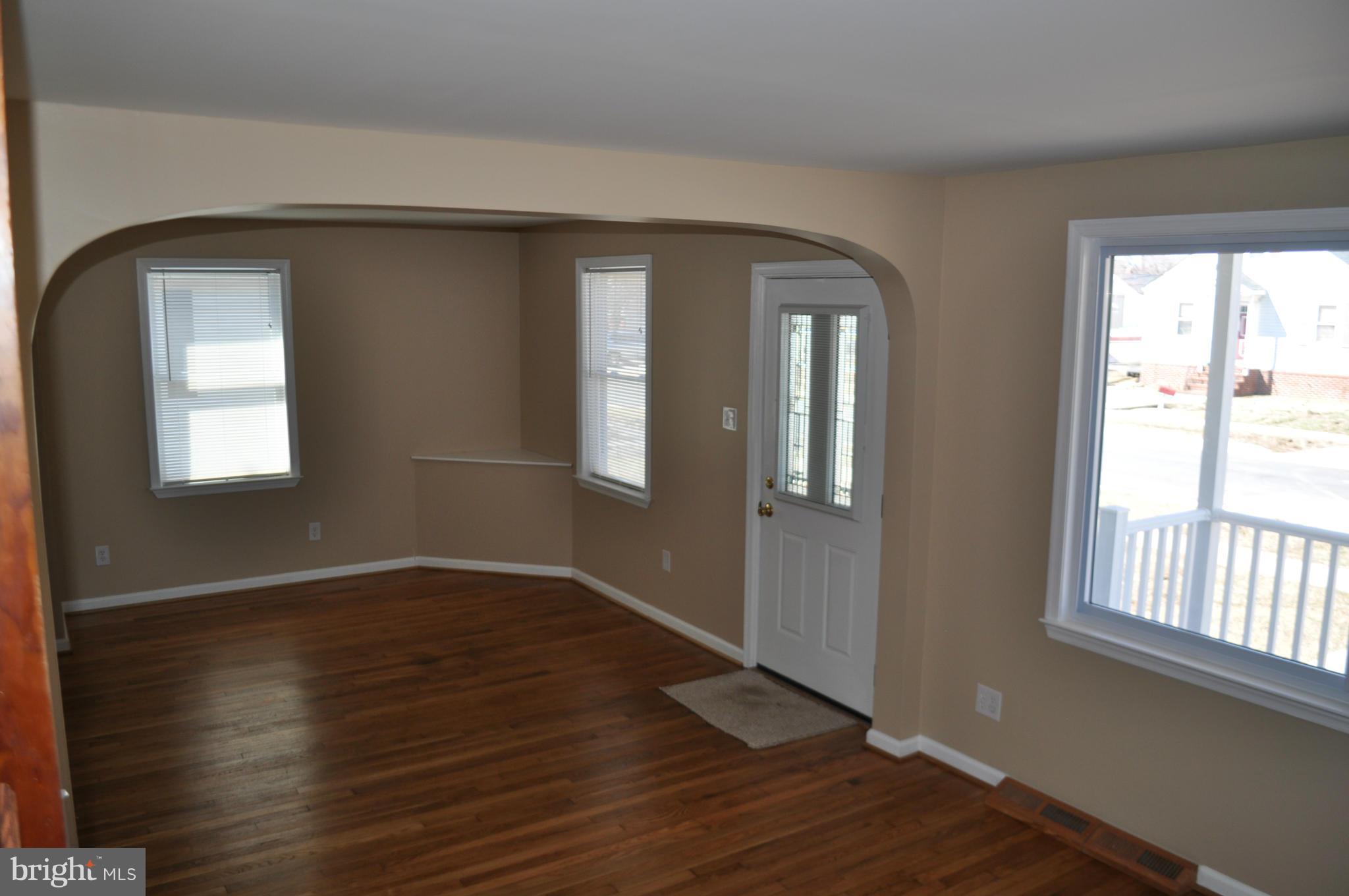 929 Woodlynn Road Baltimore, MD 21221 - Photo 10 of 25 an empty room with wooden floor and windows