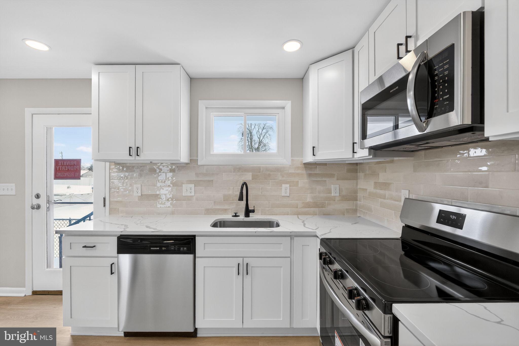 203 Antietam Road Baltimore, MD 21221 - Photo 6 of 33 a kitchen with stainless steel appliances white cabinets and stove top oven