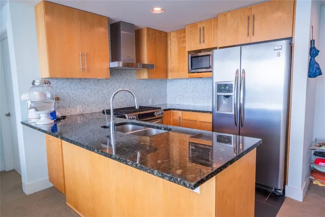 a kitchen with granite countertop a sink a stove and refrigerator