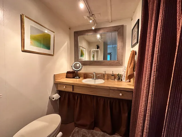 a bathroom with a granite countertop toilet sink and mirror