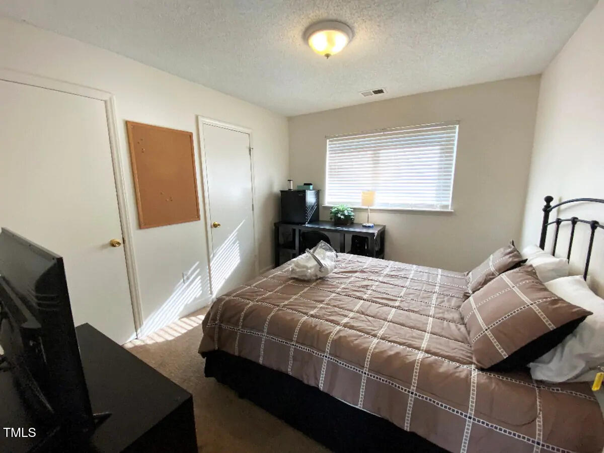 303 Smith Level Road, Unit E33 Chapel Hill, NC 27516 - Photo 5 of 25 a bedroom with a bed and a flat tv screen on a dresser