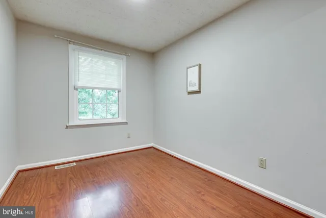 an empty room with wooden floor and a bathroom