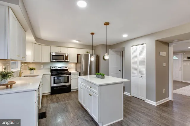a kitchen with stainless steel appliances kitchen island a sink and a refrigerator