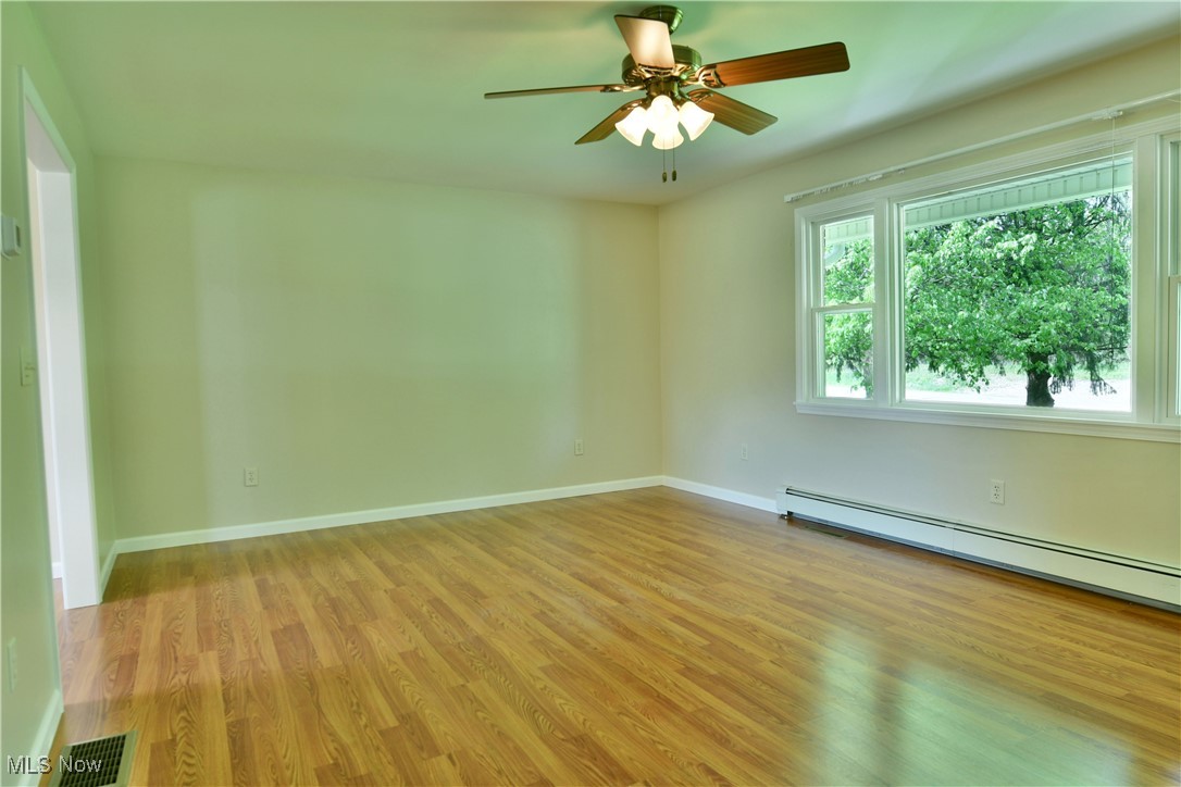 2153 Stillwagon Road Southeast Warren, OH 44484 - Photo 7 of 50 Spare room featuring baseboard heating, light wood finished floors, a ceiling fan, and baseboards