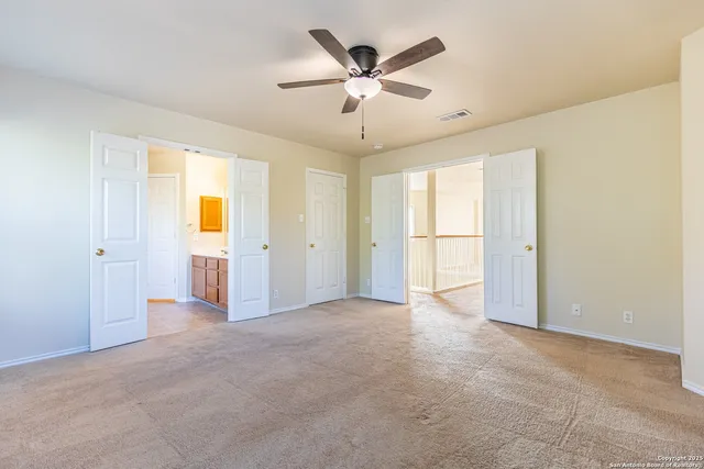 an empty room with chandelier fan and windows