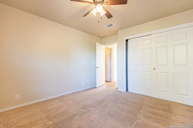 an empty room with a chandelier fan and windows
