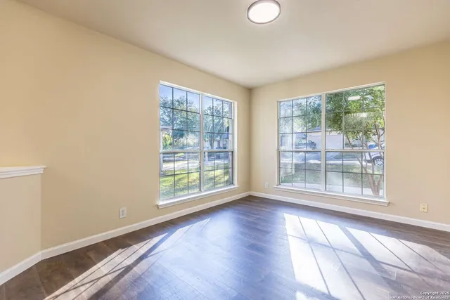 a view of an empty room with wooden floor and a window