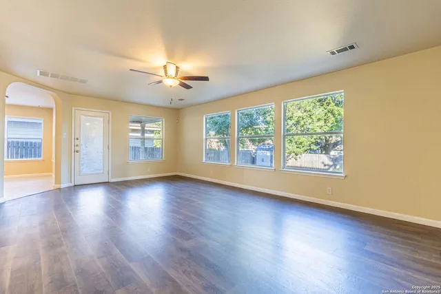 a view of an empty room with a window and wooden floor