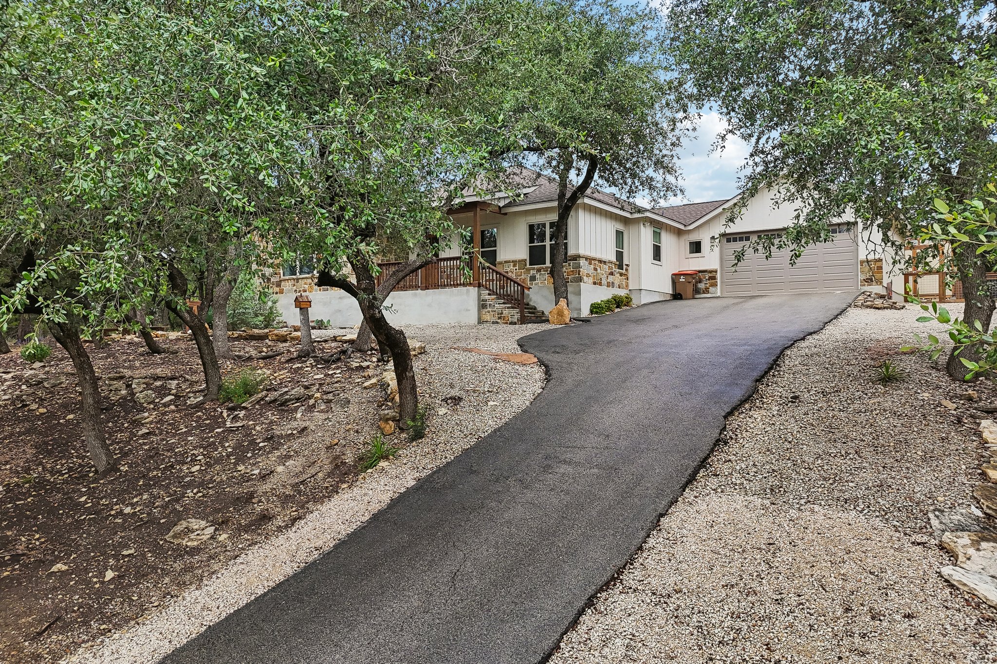 190 Magnolia Meadow Spring Branch, TX 78070 - Photo 22 of 29 A graceful paved driveway winds past mature trees towards a charming residence with a covered front porch.