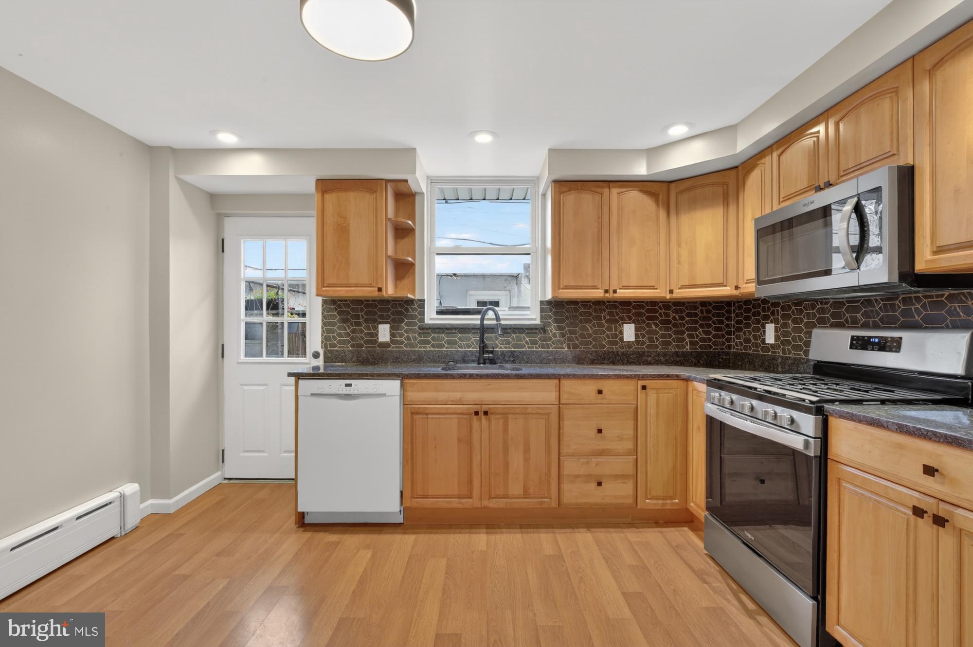 1908 South Jessup Street Philadelphia, PA 19148 - Photo 11 of 28 a large kitchen with stainless steel appliances granite countertop a stove a sink and white cabinets