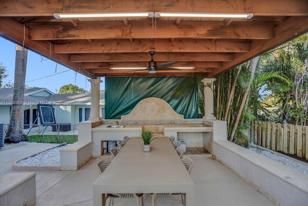960 Northwest 4th Court Boca Raton, FL 33432 - Photo 4 of 75 a view of a patio with a table and chairs under an umbrella with a small yard