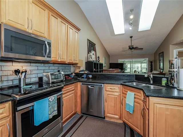 a kitchen with stainless steel appliances granite countertop a sink a stove microwave and cabinets