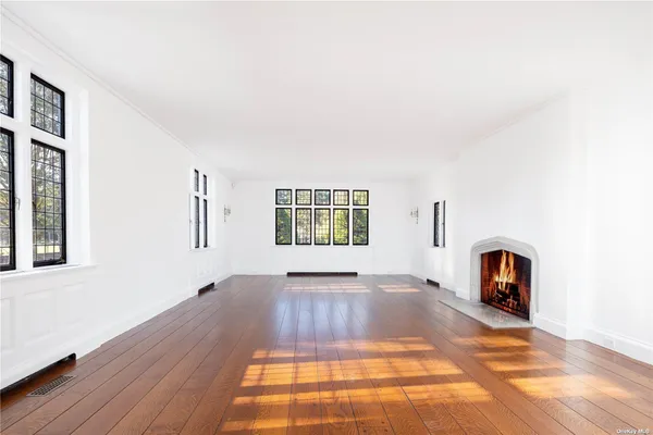 a view of an empty room with window and wooden floor