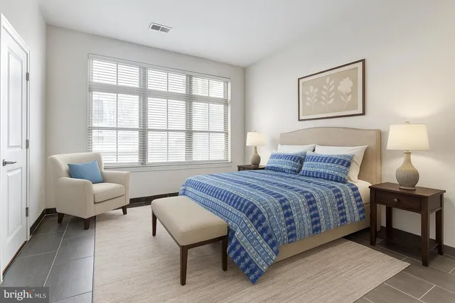 a bedroom with a bed a couch and two large window