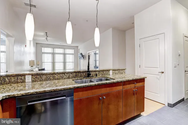 a kitchen with stainless steel appliances granite countertop a sink a counter space and a window