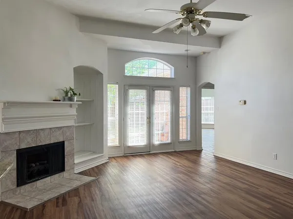 a view of an empty room with wooden floor fireplace and a window