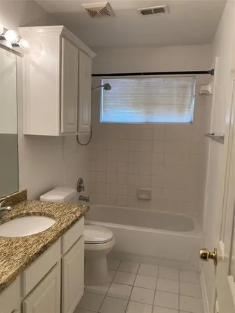 a bathroom with a granite countertop sink a toilet and bathtub