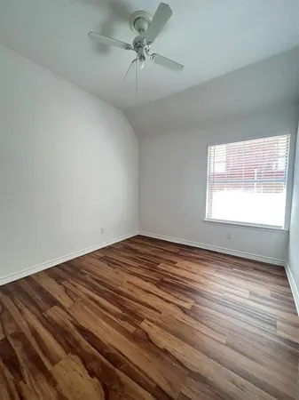 a view of empty room with window and wooden floor