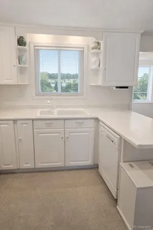 a kitchen with white cabinets and a window