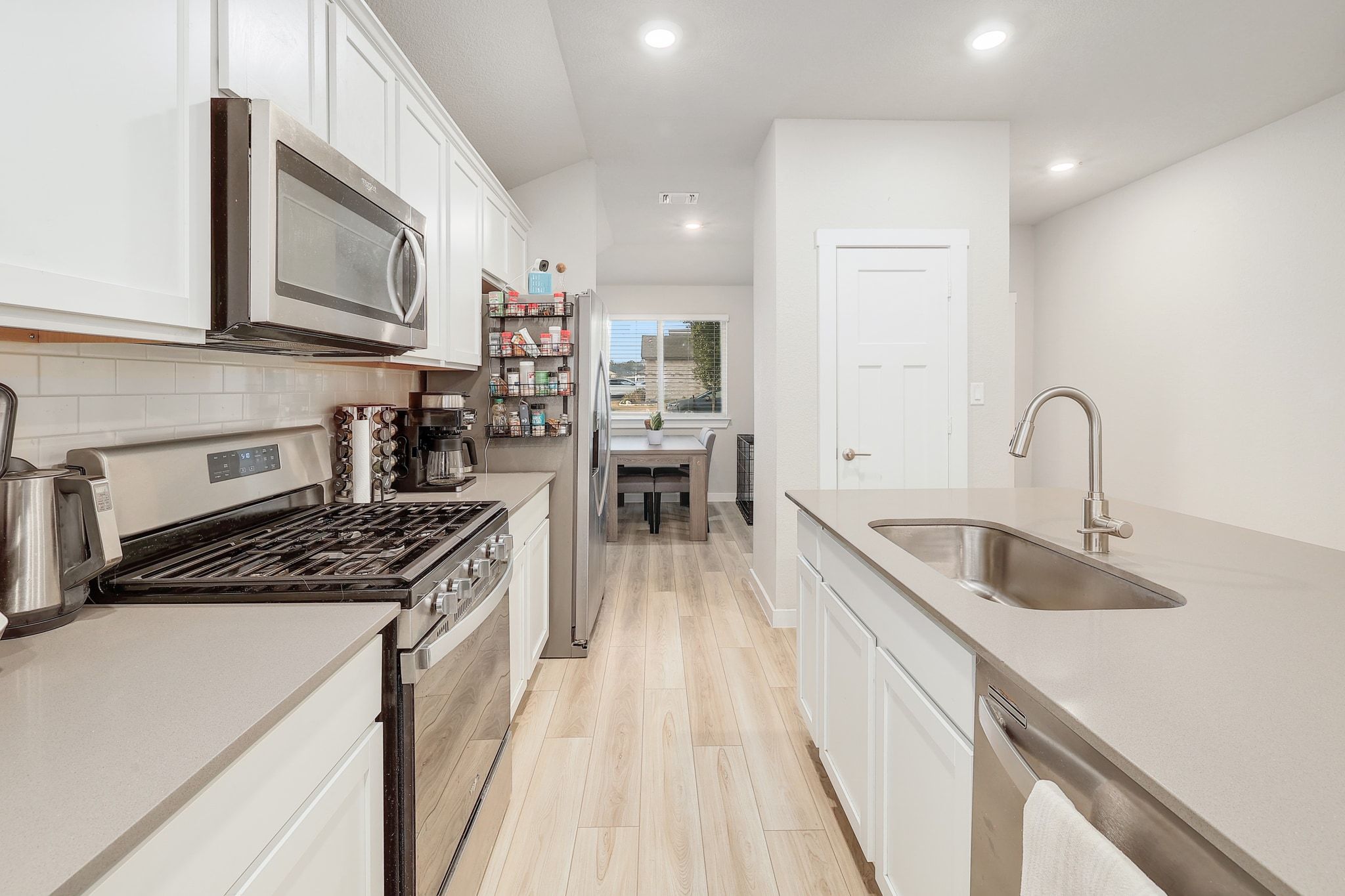 204 Halford Road Georgetown, TX 78633 - Photo 9 of 27 Kitchen featuring stainless steel appliances, white cabinetry, light wood-style floors, recessed lighting, and light stone counters