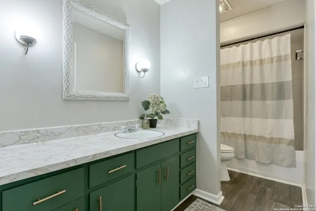 a bathroom with a granite countertop sink a toilet and a mirror