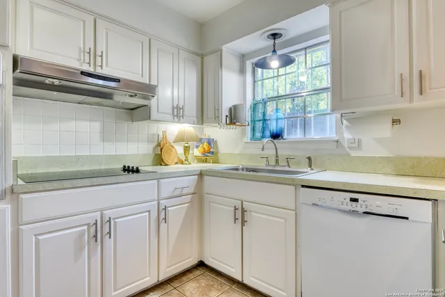 a kitchen with white cabinets and a window