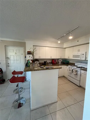 a kitchen with stainless steel appliances kitchen island granite countertop a sink and white cabinets
