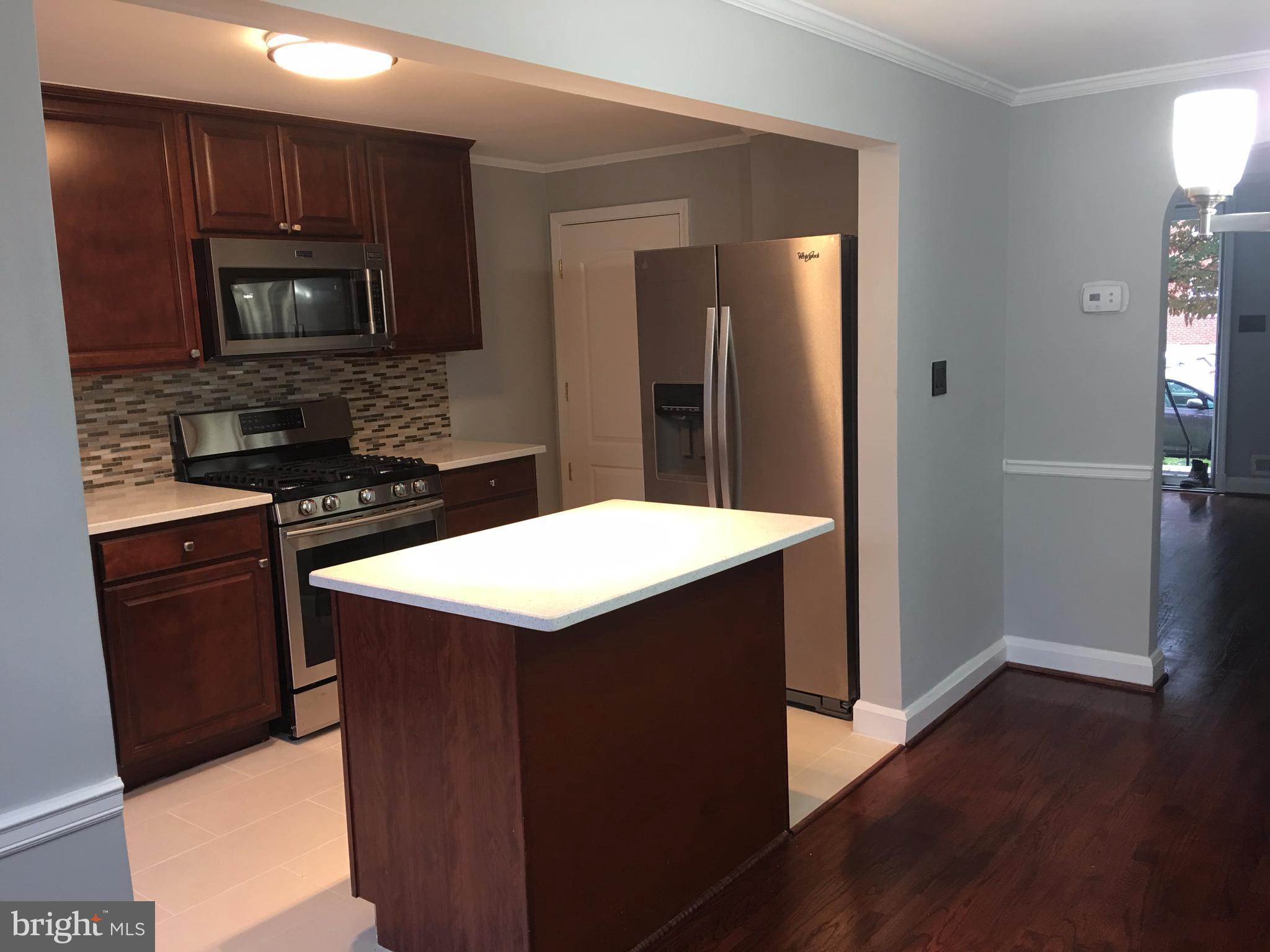 1530 Barrett Road Baltimore, MD 21207 - Photo 3 of 16 a kitchen with a sink a microwave a stove and refrigerator